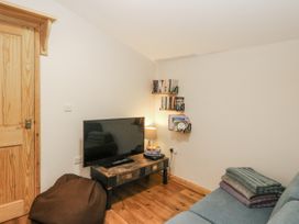 A living room with a tv and shelves at Daisy Cottage in Wigton