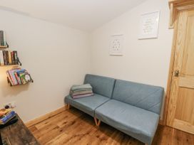 A snug with a sofa and bookshelf at Daisy Cottage in Wigton