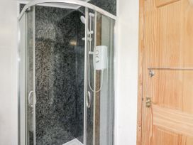 A shower with a glass enclosure and wooden door at Daisy Cottage in Wigton