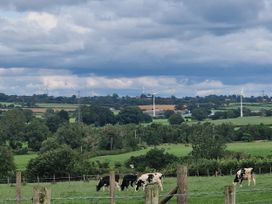A view of cows grazing in a field with wind turbines in the background at Daisy Cottage near Wigton