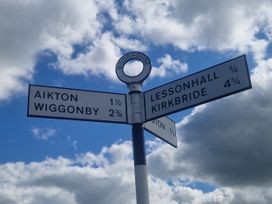 A signpost indicating distances to Aikton, Wiggonsby, Lessonhall, and Kirkbride near Moorhouse