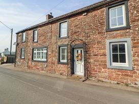 An exterior view of a stone house with a door and windows at Daisy Cottage near Wigton