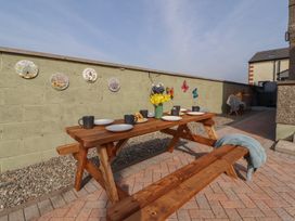 An outdoor dining area with a wooden table and bench at Daisy Cottage near Wigton