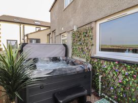 An outdoor area with a hot tub next to a wall at Daisy Cottage near Wigton