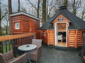 An outdoor deck with a round table and two wicker chairs next to a wooden hut labeled Hobbit Hut in Dungiven Londonderry