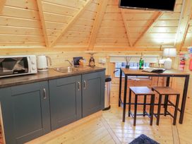 A wooden kitchen area with a microwave kettle sink and a dining table with two stools at Hexagon Hut - Dec Update in Dungiven Londonderry