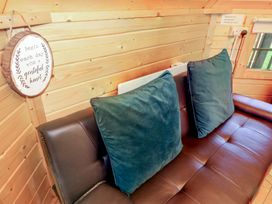 A brown leather sofa with two large green cushions and a wooden wall with a round sign at Hexagon Hut - Dec Update in Dungiven Londonderry