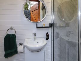 A bathroom with a sink mirror towel toilet paper holder and a shower at Hexagon Hut - Dec Update in Dungiven Londonderry
