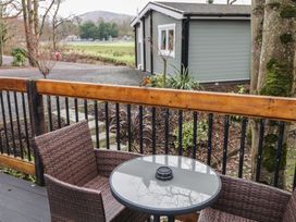 A small patio with a round glass table and two wicker chairs overlooking a garden and a green cabin at Hexagon Hut - Dec Update in Dungiven Londonderry