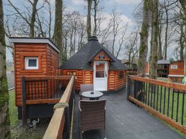 An outdoor wooden hut called Hobbit Hut with a small round table and two chairs on a deck surrounded by trees at Hexagon Hut - Dec Update in Dungiven Londonderry