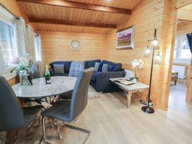 A dining area with four chairs around a round table and a living area with a sofa and side table in a wooden interior at Mill View in Dungiven Londonderry