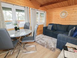 A wooden interior room with a round table and four chairs next to a blue sofa and a fluffy rug at Mill View in Dungiven Londonderry