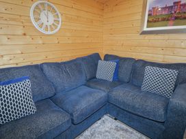A blue sectional sofa with patterned cushions in a wooden paneled room with a clock and framed picture at Mill View in Dungiven Londonderry