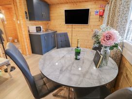 A dining area with a round marble table and black chairs next to a kitchenette with microwave and sink at Mill View in Dungiven Londonderry