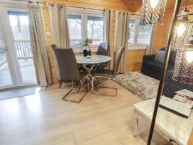 A dining area with a round table and four chairs next to windows with curtains in a wooden room at Mill View in Dungiven Londonderry
