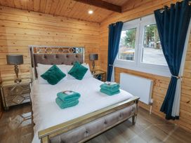 A bedroom with a double bed with teal pillows and towels two bedside tables with lamps and a window with blue curtains at Mill View in Dungiven Londonderry