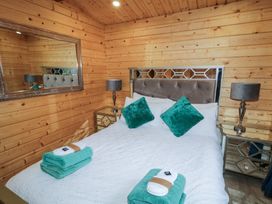 A bedroom with a bed with teal pillows and towels two bedside tables with lamps and a large mirror on wooden walls at Mill View in Dungiven Londonderry