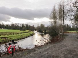 A river flowing alongside a gravel path with trees and a parking sign at Mill View in Dungiven Londonderry