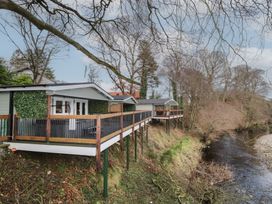 Cabins on stilts along a riverbank with bare trees at Owenbeg in Dungiven Londonderry