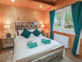 A bedroom with a bed with green pillows and towels bedside tables with lamps and a window with green curtains at Owenbeg in Dungiven Londonderry
