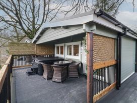 An outdoor deck with wicker chairs around a table and a covered hot tub at Owenbeg in Dungiven Londonderry