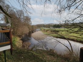 A river flowing through a wooded area with a balcony on the left side and fields in the background at Owenbeg Dungiven Londonderry