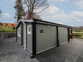 An exterior view of a small green building with white trim windows and a black deck at The Roe in Dungiven Londonderry