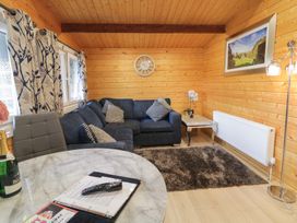 A living room with a blue sofa a round table a remote control and a bottle at The Roe in Dungiven Londonderry