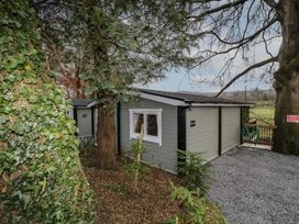 An exterior view of a small cabin surrounded by trees and plants with a gravel path at The Castle in Dungiven Londonderry