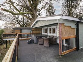 An outdoor deck area with a hot tub wicker chairs and a round table surrounded by trees at The Castle in Dungiven Londonderry