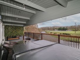 A covered balcony with a hot tub table and chairs overlooking a river and grassy field at The Castle in Dungiven Londonderry