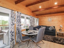 A wooden dining and living area with a round table and grey chairs a dark sofa a wall clock and patterned curtains at The Castle in Dungiven Londonderry