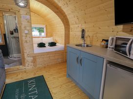 An interior view of a wooden cabin with a kitchen area a bed with towels and a bathroom with a shower at Hazel in Dungiven Londonderry