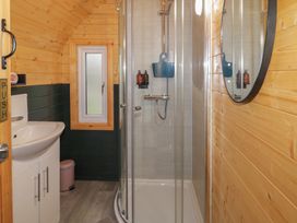 A bathroom with a shower enclosure a sink with cabinet a toilet a small window and wooden panel walls at Hazel in Dungiven Londonderry