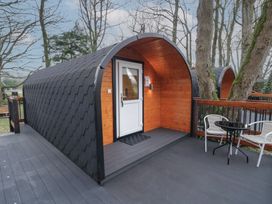A small arched wooden cabin with a white door on a wooden deck with two chairs and a round table at Hazel in Dungiven Londonderry