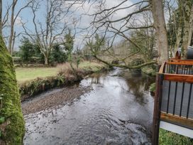A river with trees on both sides and a wooden deck overlooking the water at Hazel in Dungiven Londonderry