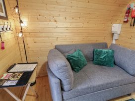 A corner of a room with a grey sofa with green cushions and a small table holding papers and a remote control at Juniper in Dungiven Londonderry