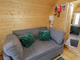 A wooden room with a gray sofa and green cushions next to a door leading to a bathroom at Juniper in Dungiven Londonderry