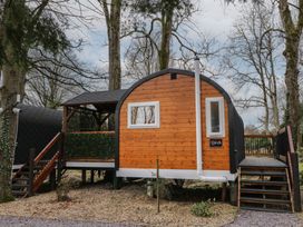 A wooden pod elevated on stilts with stairs on each side surrounded by trees at Birch in Dungiven Londonderry
