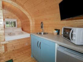 A wooden cabin interior with a bed towels kitchen sink microwave fridge and a wall-mounted TV at Birch in Dungiven Londonderry