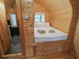 A wooden bedroom with a double bed and folded towels next to a bathroom with a small window at Birch in Dungiven Londonderry