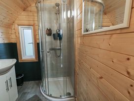 A bathroom with a glass shower enclosure a sink with cabinet and a small window at Birch in Dungiven Londonderry