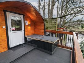 A wooden pod with a white door on a deck with a countertop and railing by a river at Yew in Dungiven Londonderry