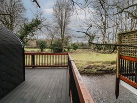 A wooden deck with railings overlooking a river and leafless trees at Yew in Dungiven Londonderry