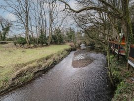 A river with trees on both sides and wooden cabins on the right bank at Yew in Dungiven Londonderry