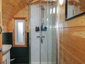 A bathroom with a wooden arched ceiling a glass shower enclosure a small window and a white sink at Yew in Dungiven Londonderry
