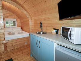 A wood-paneled room with a bed near a window and a kitchen counter with a sink microwave and small fridge at Elm in Dungiven Londonderry