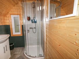 A bathroom with a corner shower enclosure a sink cabinet a small window and wooden panel walls at Elm in Dungiven Londonderry