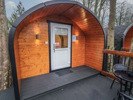 A wooden pod cabin with a white door and outdoor seating at Hawthorn in Dungiven Londonderry