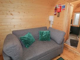 A gray sofa with two green pillows in a wooden room next to a small bathroom at Hawthorn in Dungiven Londonderry